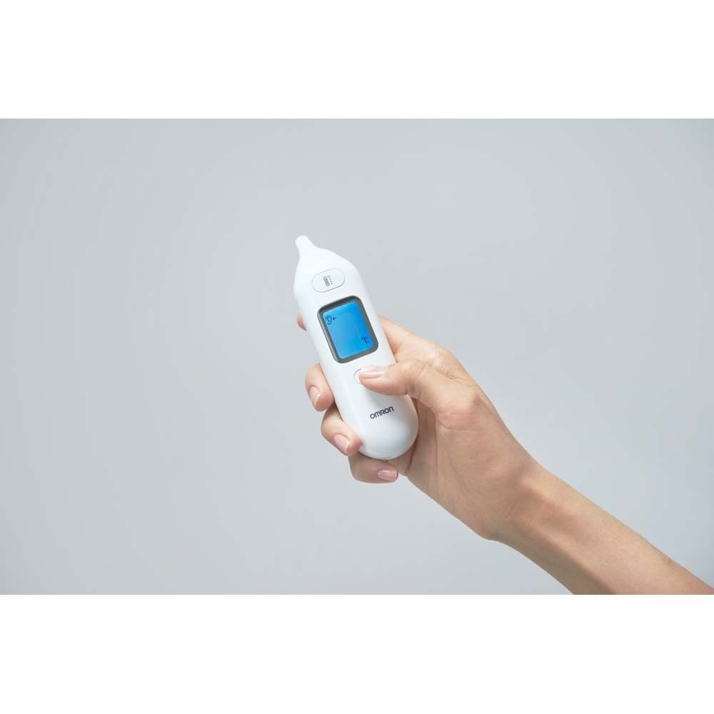 Hand hält weißes Ohrthermometer. Display zeigt Temperatur. OMRON-Logo.