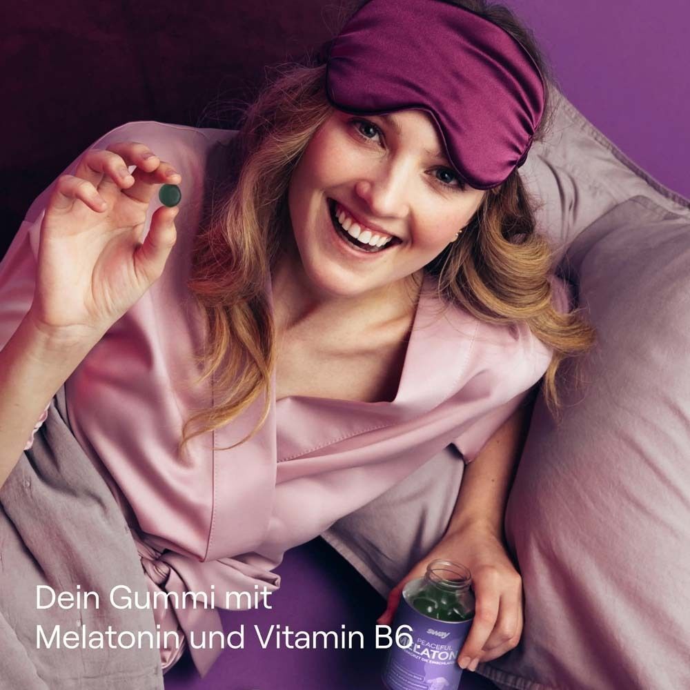 Eine Frau hält eine Gummibärchen von "sway Peaceful Melatonin" in der Hand. Sie trägt eine Schlafmaske und lächelt.