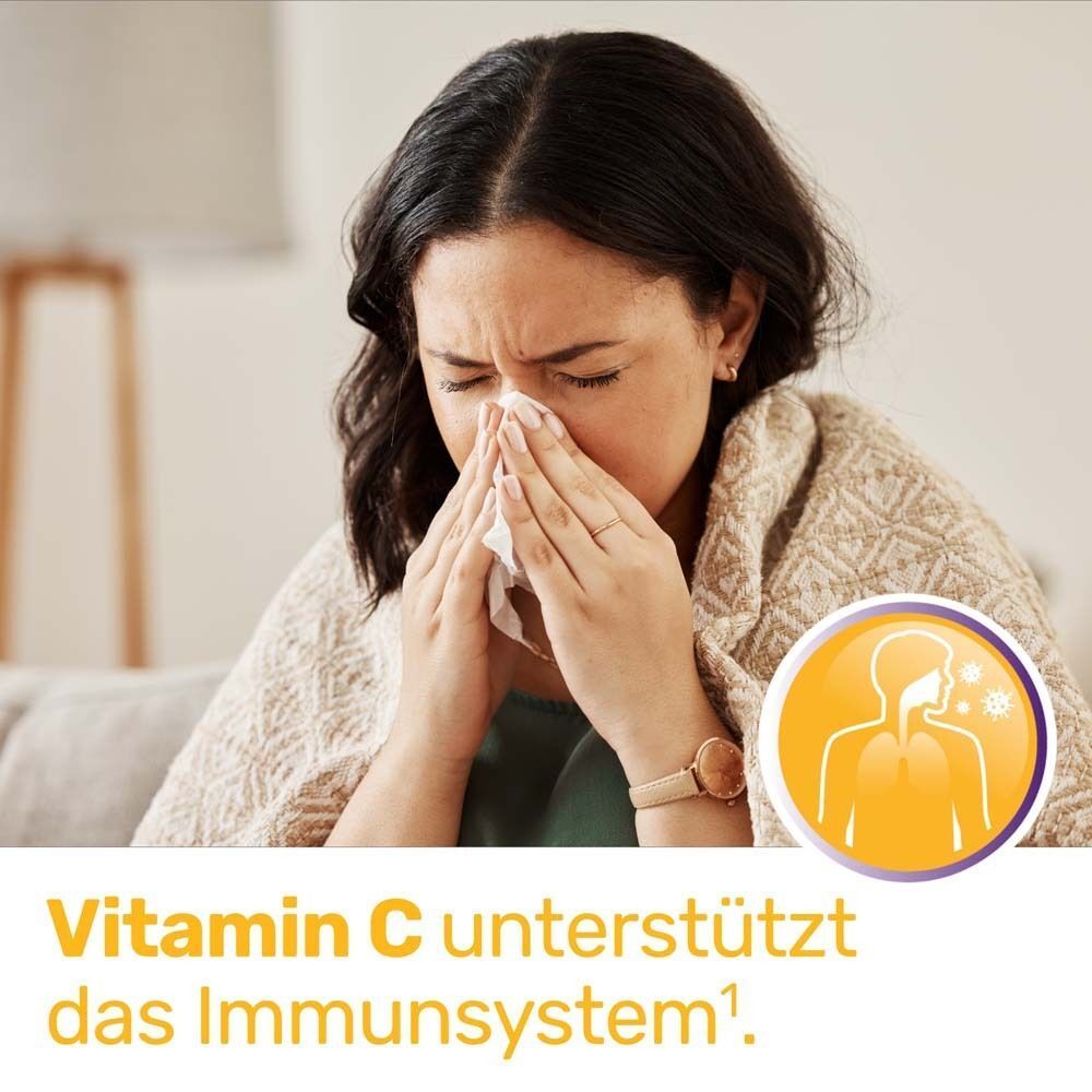 Frau mit Taschentuch. Text: Vitamin C unterstützt das Immunsystem. Illustration: Lunge und Immunsystem. Hintergrund: Wohnzimmer.