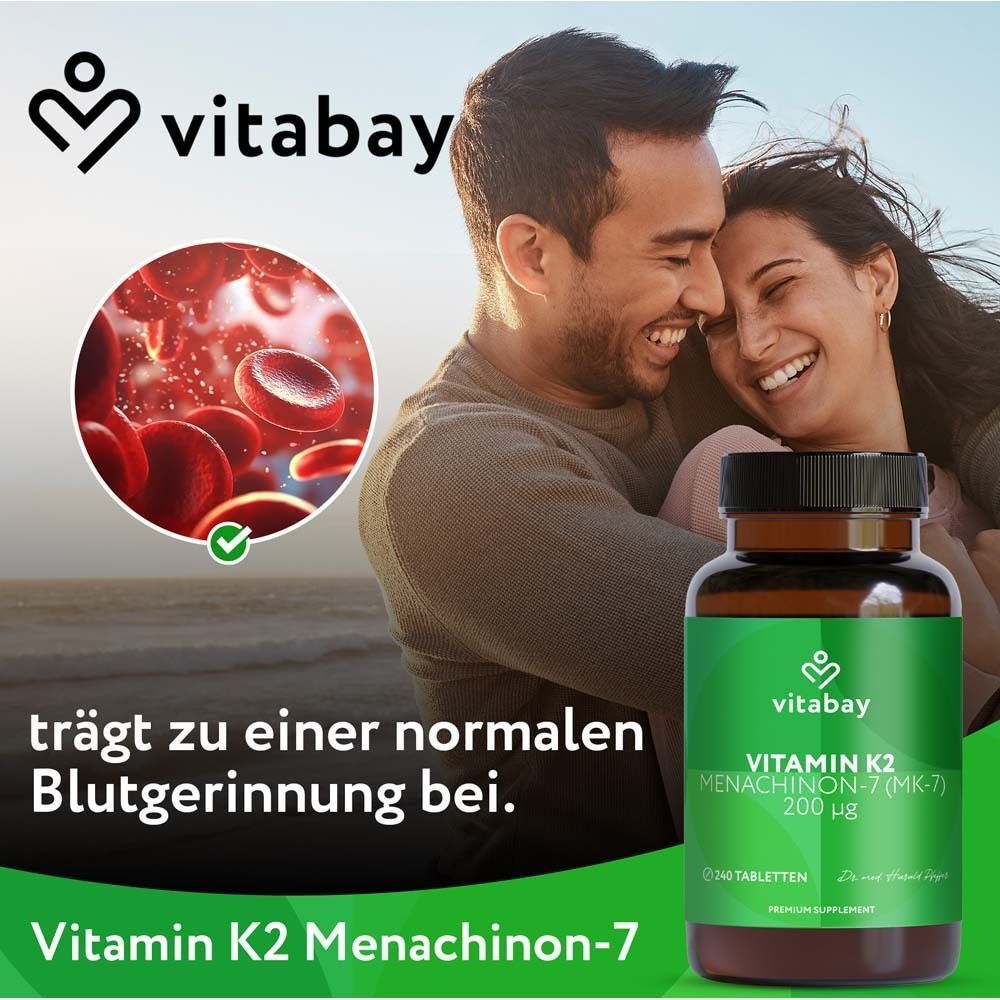 Eine braune Flasche mit grünem Etikett. Aufschrift: Vitamin K2 200 µg. Paar umarmt sich im Hintergrund.