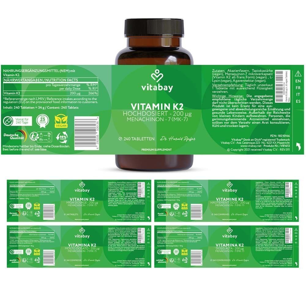 Braune Flasche mit Etikett. Aufschrift: Vitamin K2. Mehrere Etiketten liegen daneben.