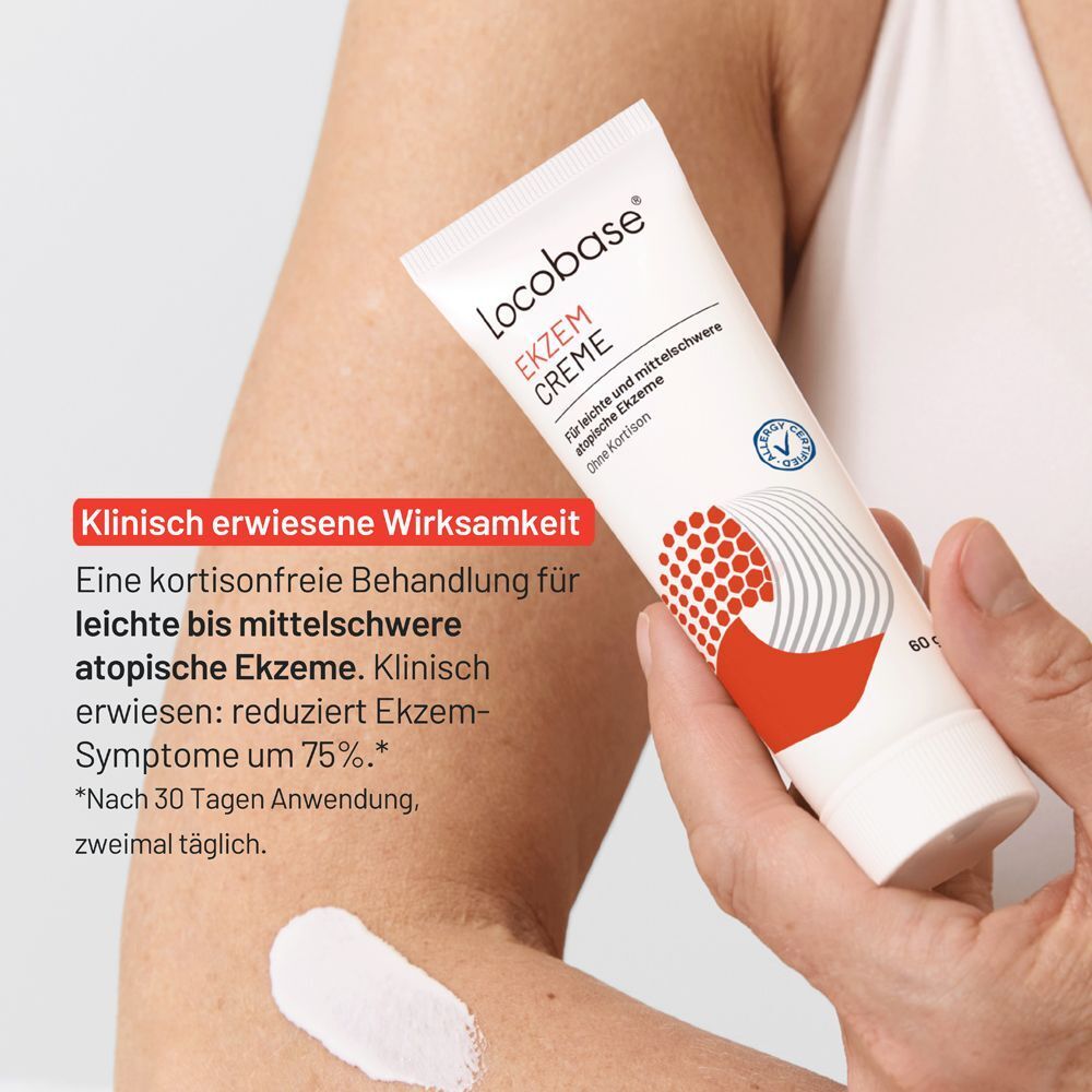 Hand hält eine Tube Locobase Ekzem Creme auf einem Arm mit Ekzem.