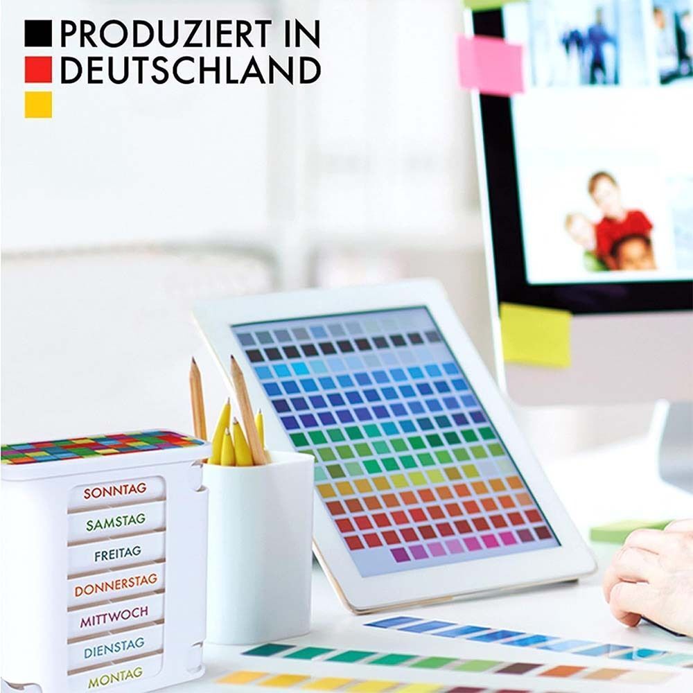 Weiße Pillendose mit 7 Fächern für Wochentage. Bunter Deckel. Auf Schreibtisch mit Tablet und Farbmuster.