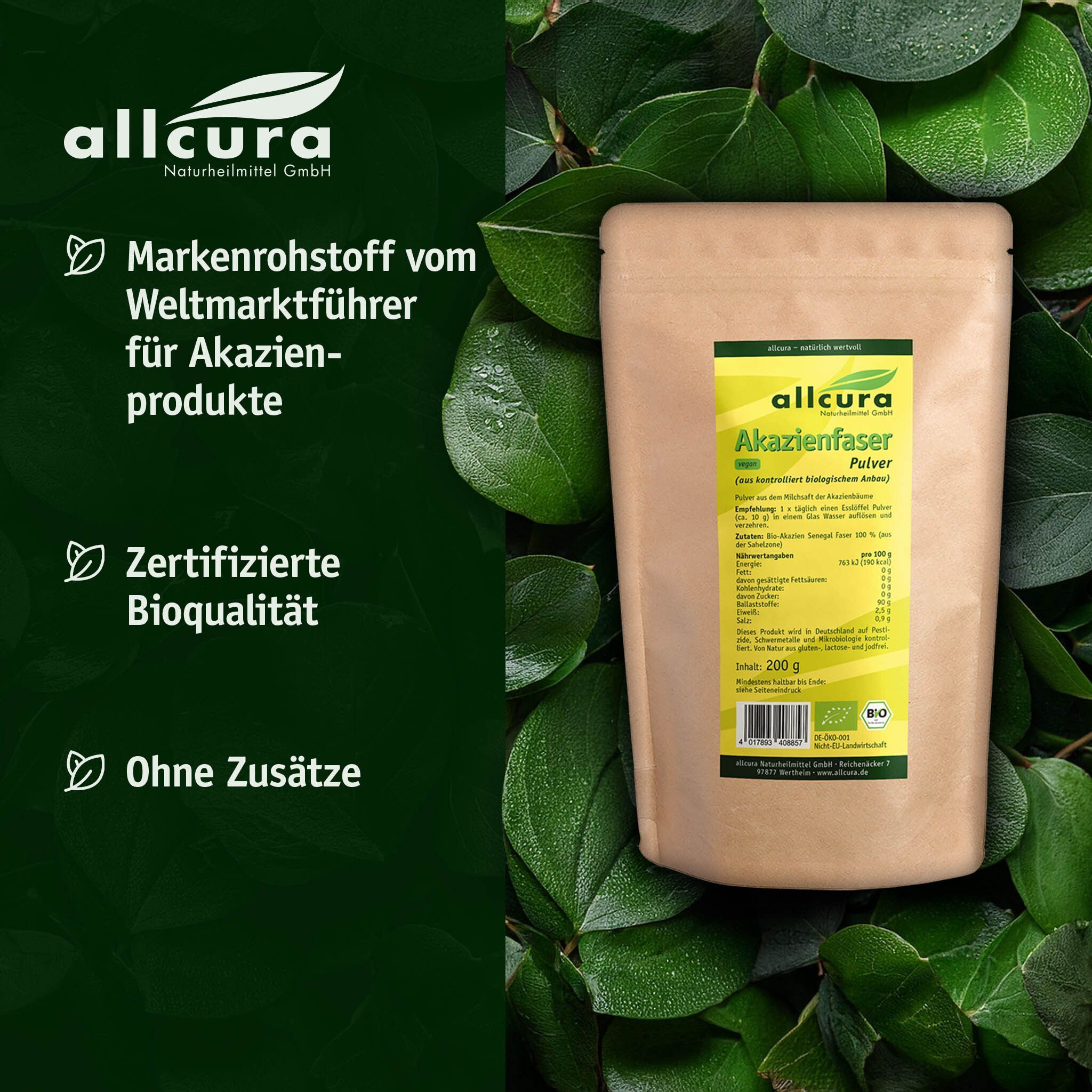 Beutel AKAZIENFASER Pulver Bio auf Blättern. Braune Papierverpackung mit gelbem Etikett. Aufschrift: allcura, Akazienfaser Pulver, Bio. 200 g. Bio-Siegel.