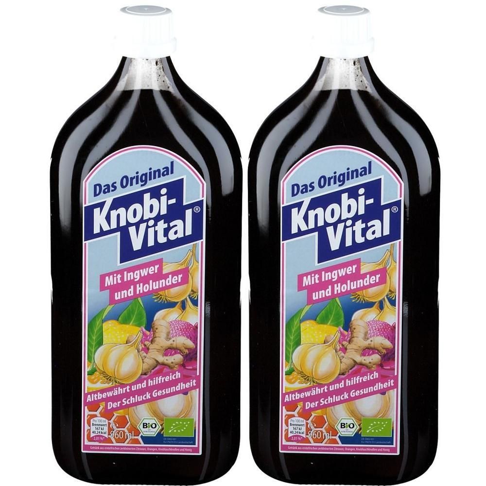 Zwei Flaschen Knobi-Vital mit Ingwer und Holunder. Dunkle Flüssigkeit, weiße Verschlüsse. Etikett mit Abbildungen von Knoblauch, Ingwer und Holunder.