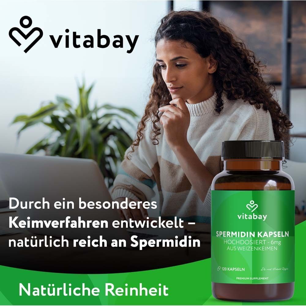 Frau am Laptop. Daneben eine Flasche mit Kapseln. Aufschrift: Spermidin Kapseln, 6 mg, aus Weizenkeimen. Marke: Vitabay.