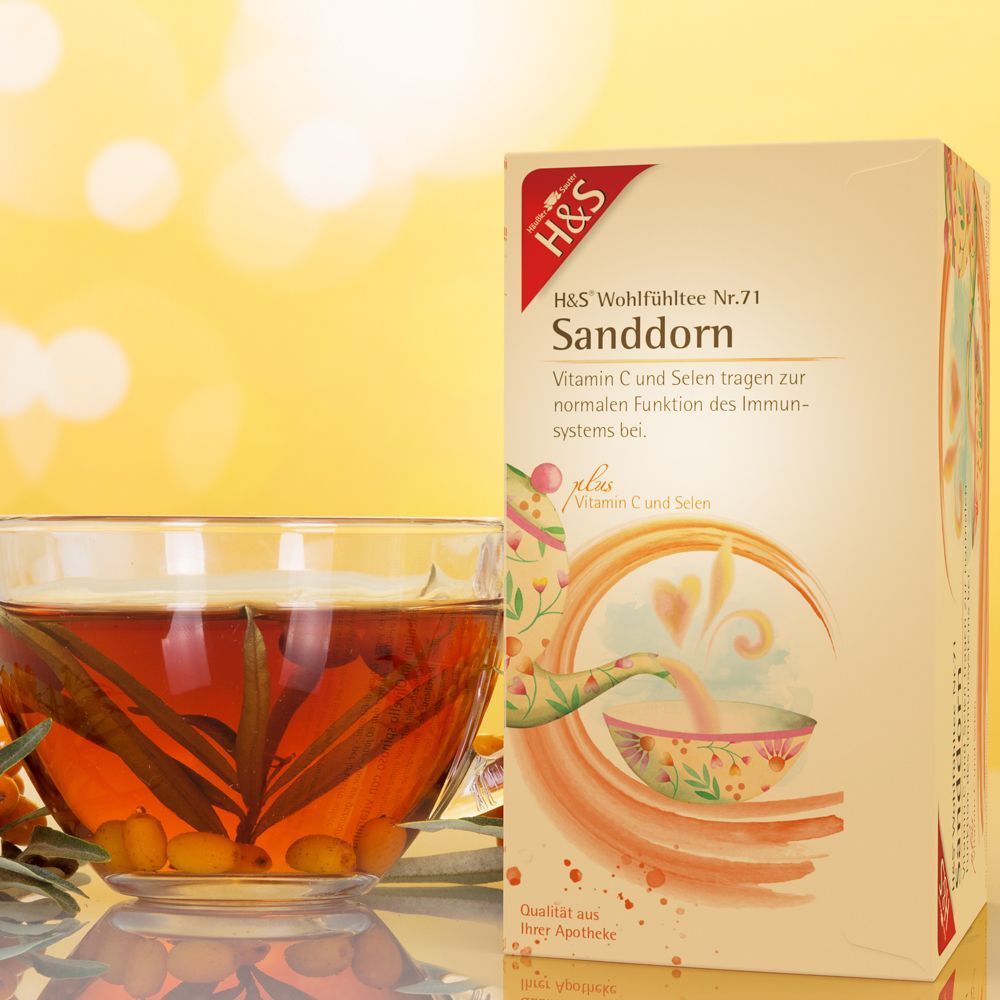 H&S Sanddorn Tee Packung neben einer Tasse Tee. Teebeutel im Glas. Gelber Hintergrund mit Bokeh-Effekt.