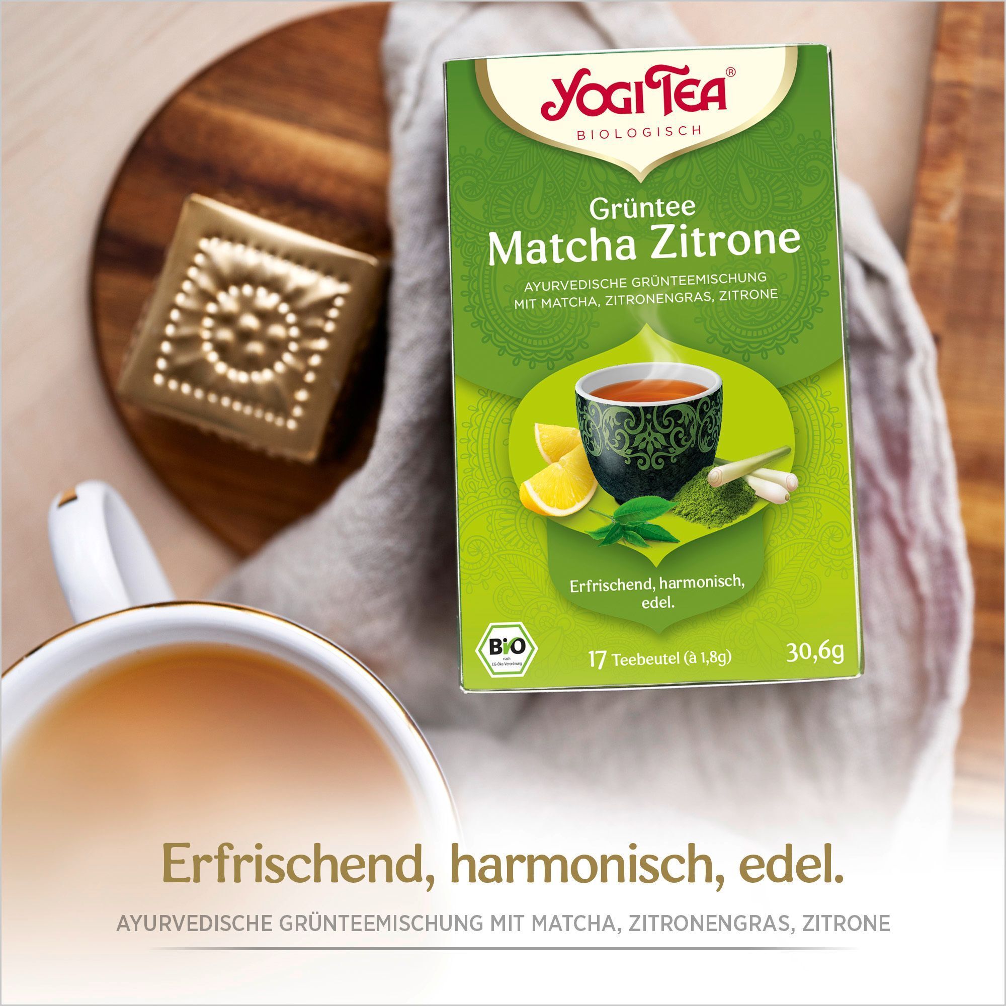 Grüne Yogi Tea-Verpackung neben einer Tasse Tee. Aufdruck: Grüntee Matcha Zitrone, 17 Teebeutel, Bio-Siegel.