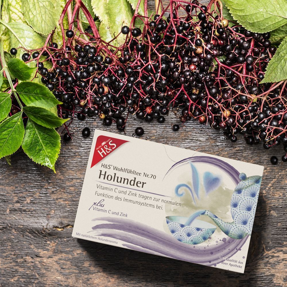 H&S Holunder Tee-Packung mit Holunderbeeren und Blättern. Produktname und Logo sichtbar. Auf Holzuntergrund.