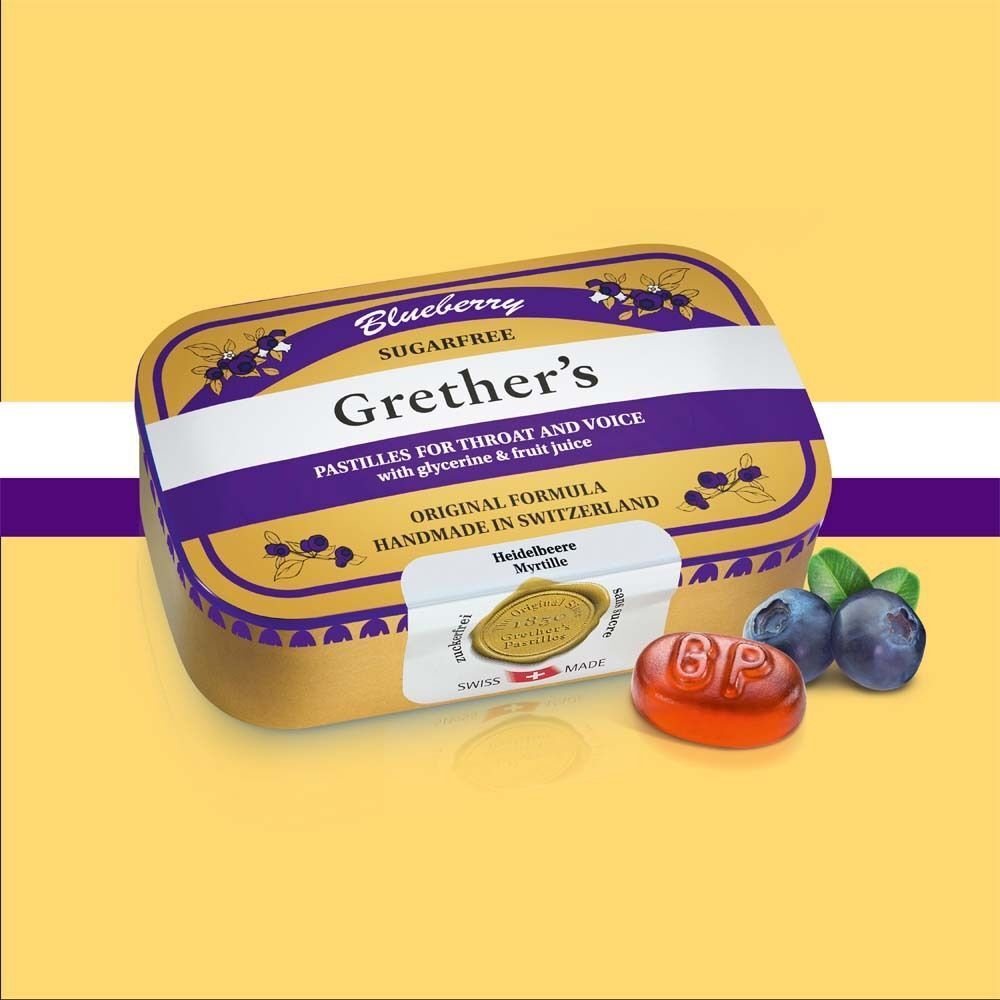 Eine Packung Pastillen mit "Grether's"-Logo. Blaubeeren und eine Pastille daneben. Aufschrift: "Sugarfree".
