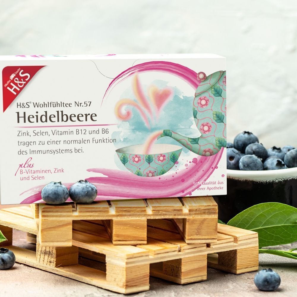 H&S Heidelbeere Tee-Packung auf Holzpalette mit Blaubeeren. Aufdruck: Nr.57, Zink, Selen, Vitamin B12 und B6.