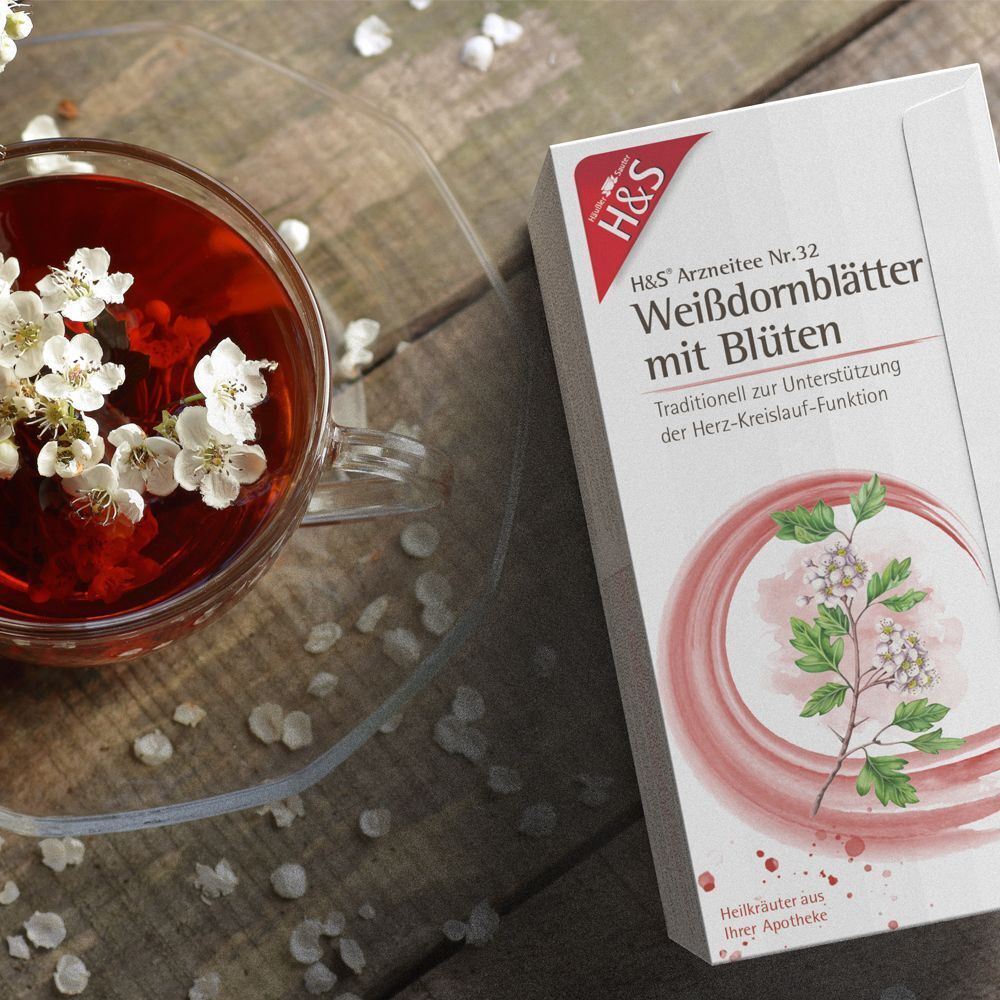 H&S Weißdornblätter mit Blüten Tee Nr. 32 neben einer Tasse Tee mit Blüten.