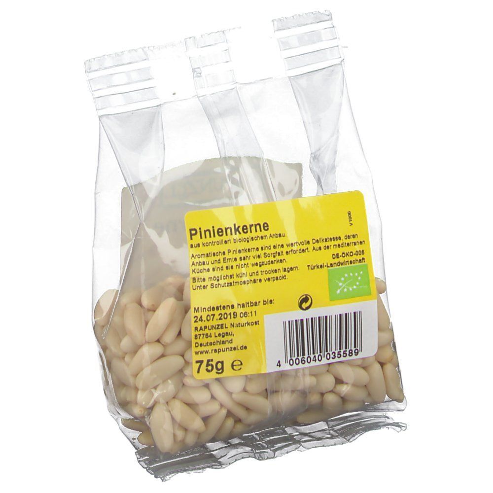 Transparenter Beutel mit Pinienkernen. Gelbes Etikett mit "RAPUNZEL" und "Pinienkerne". 75g. Bio-Siegel. Text und Barcode auf dem Etikett.