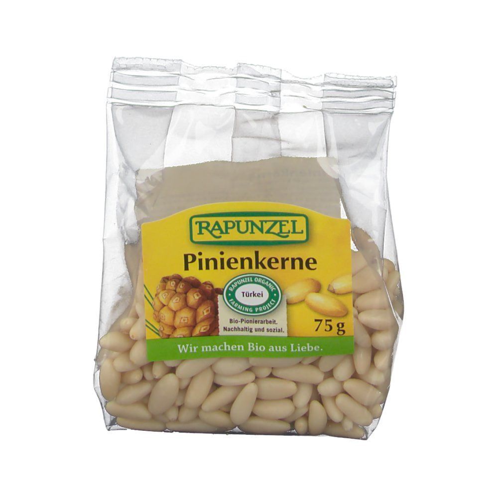 Transparenter Beutel mit Pinienkernen. Gelbes Etikett mit "RAPUNZEL" und "Pinienkerne". 75g. Bio-Siegel. Aufschrift: "Wir machen Bio aus Liebe."