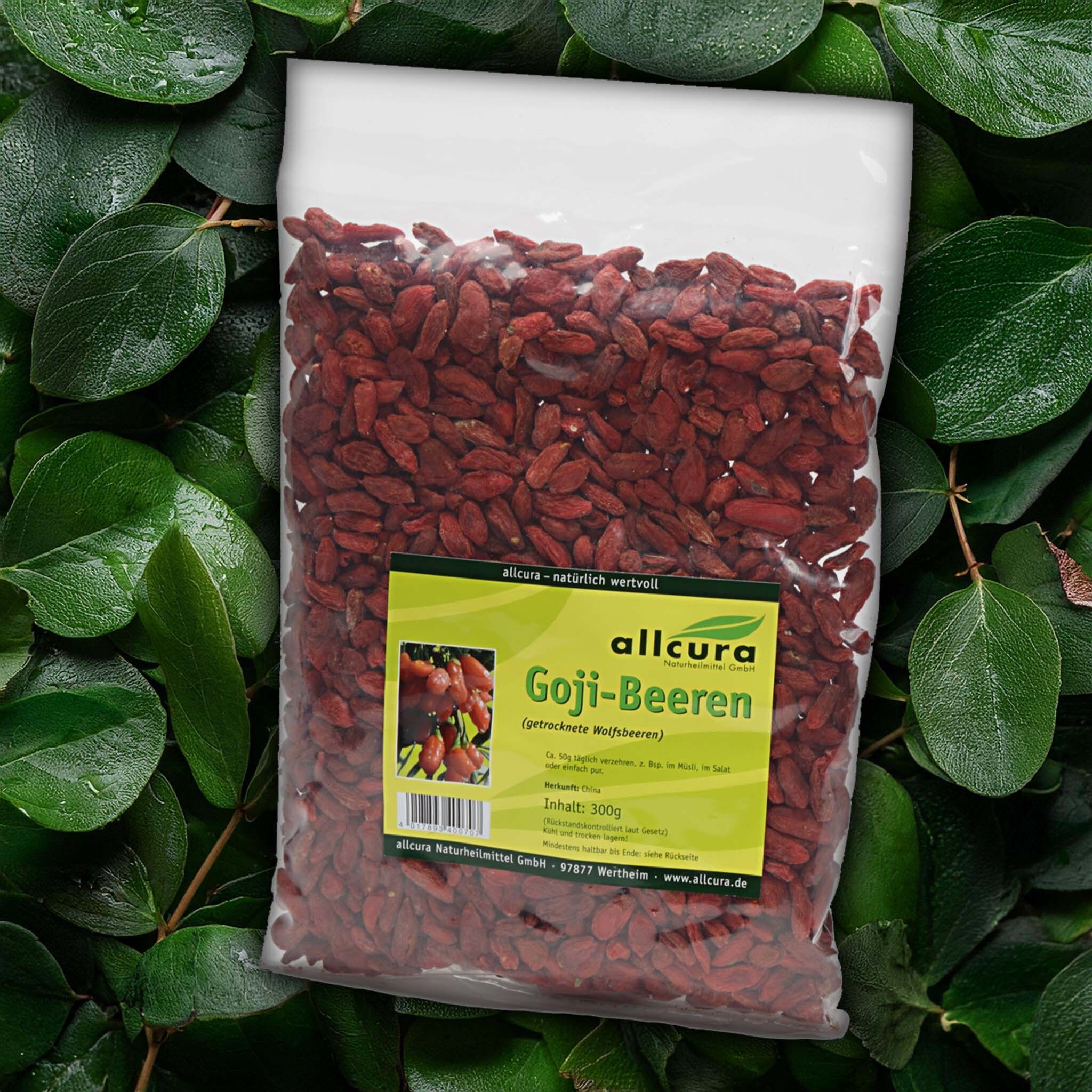Goji-Beeren in einem transparenten Beutel. Aufdruck mit Produktname und Logo. Hintergrund: grüne Blätter.