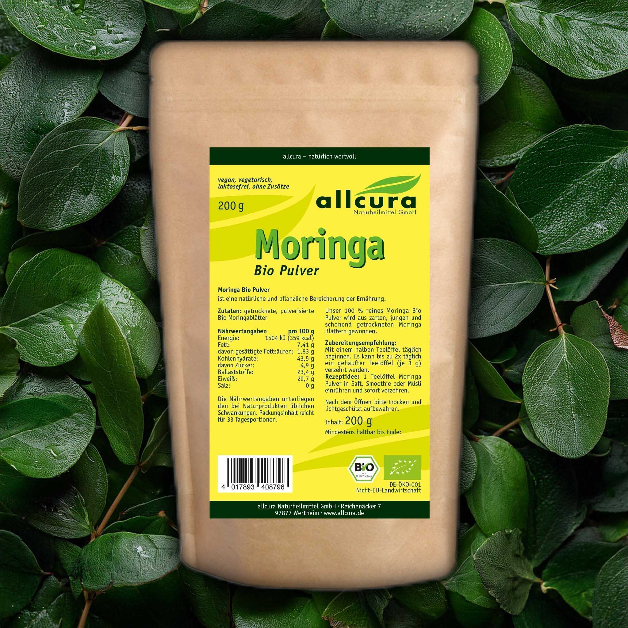 Brauner Beutel MORINGA BIO Pulver auf Blättern. Gelbes Etikett mit Aufschrift: allcura, Moringa Bio Pulver, 200g. Bio-Siegel. Nährwertangaben.