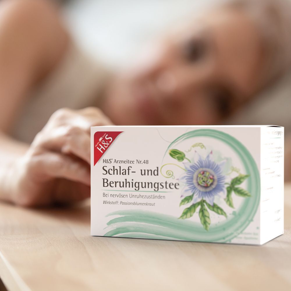 Packung H&S® Schlaf- und Beruhigungstee neben einer Person, die sich ausruht.
