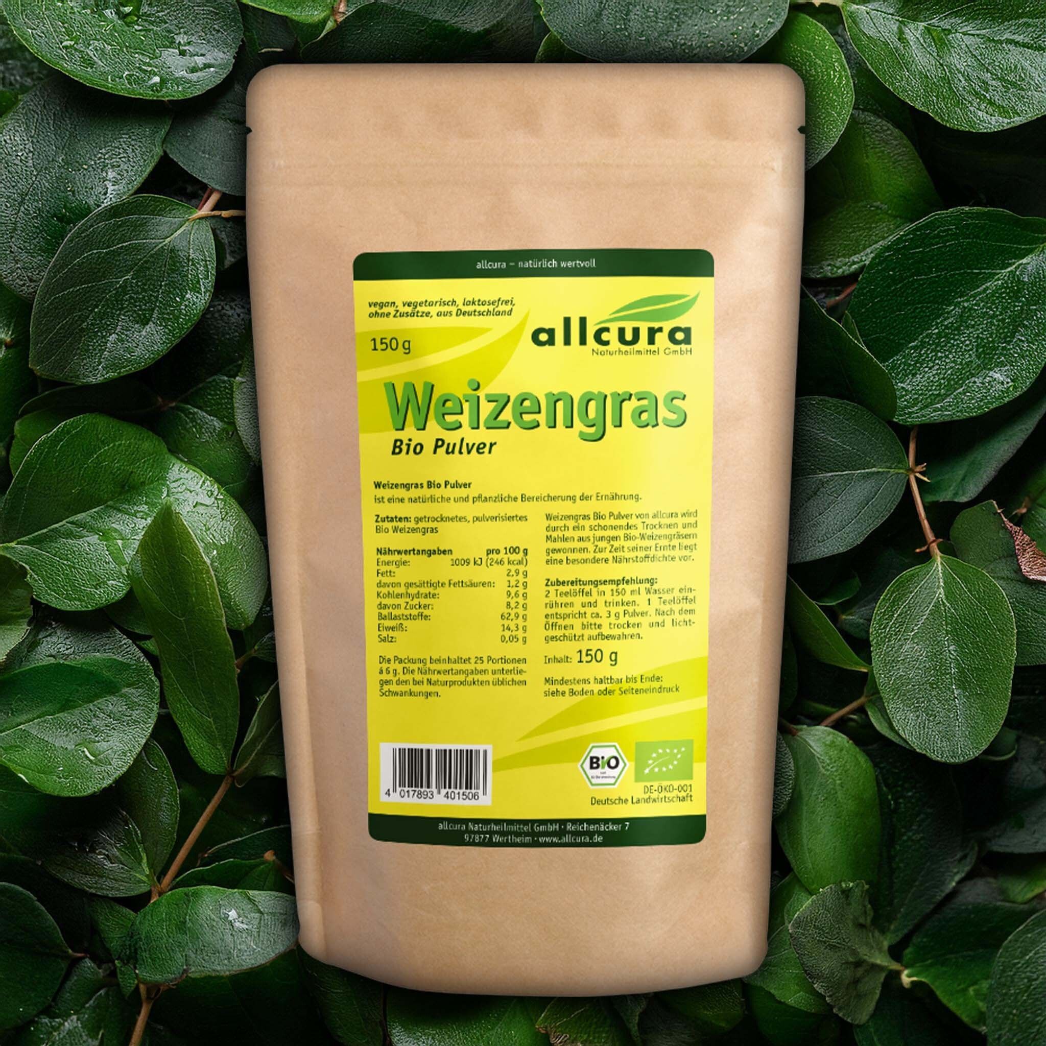 Beutel WEIZENGRAS PULVER KBA Bio auf Blättern. Braune Papierverpackung mit gelbem Etikett. Aufschrift: allcura, Bio Pulver, 150g. Bio-Siegel.