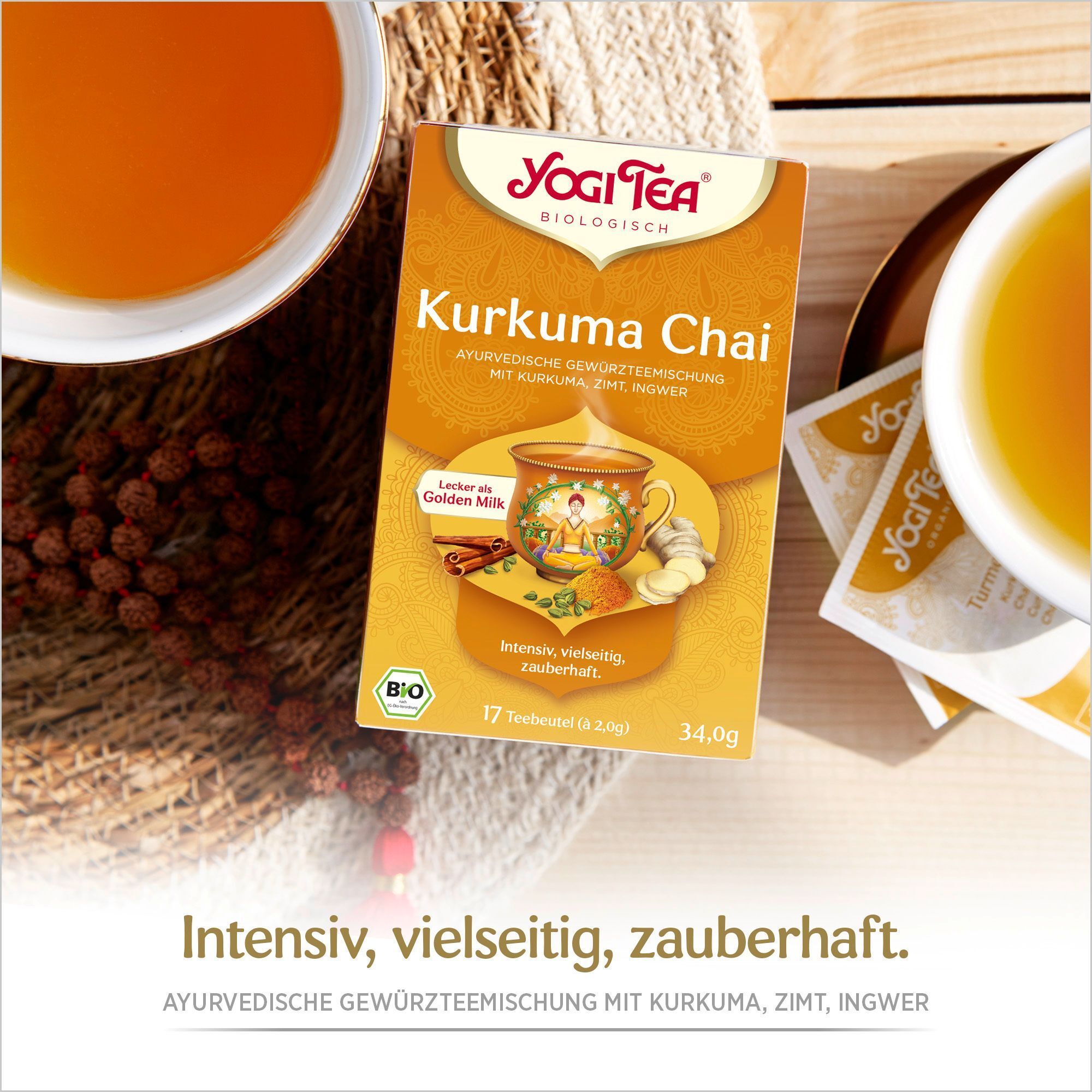 YOGI TEA Kurkuma Chai Bio Packung auf Holz. Tasse Tee, Teebeutel und Zutaten. Logo und Produktname sichtbar.