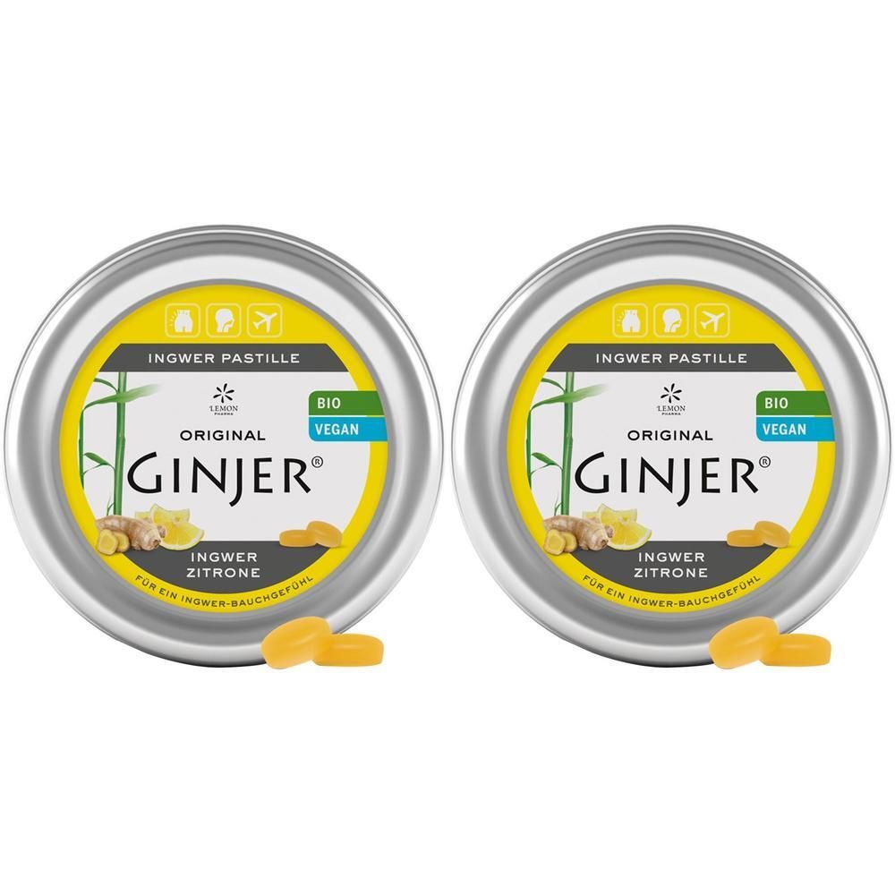 Zwei runde Metalldosen mit gelbem Etikett. Aufschrift: GINJER, Ingwer Pastille, Bio, Vegan. Einige Pastillen liegen daneben.