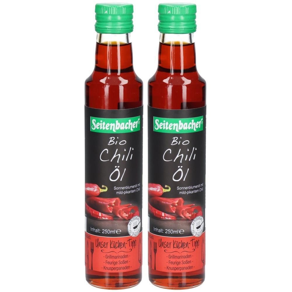 Zwei Flaschen Bio Chili Öl. Schwarzes Etikett mit roter Chili-Abbildung. Grüner Deckel. Text: Seitenbacher, Bio Chili Öl.