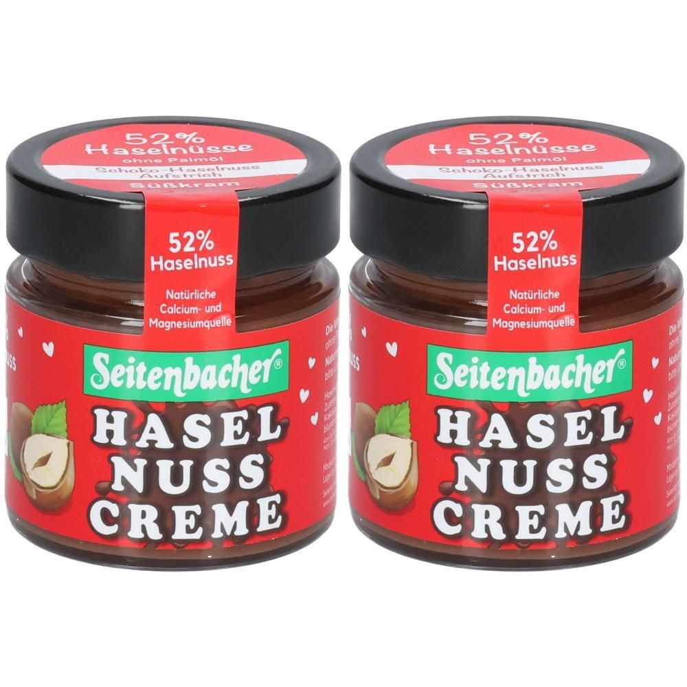 Zwei Gläser Seitenbacher Haselnuss Creme. Roter Hintergrund, schwarzer Deckel. Aufschrift: 52% Haselnuss, Haselnuss Creme.