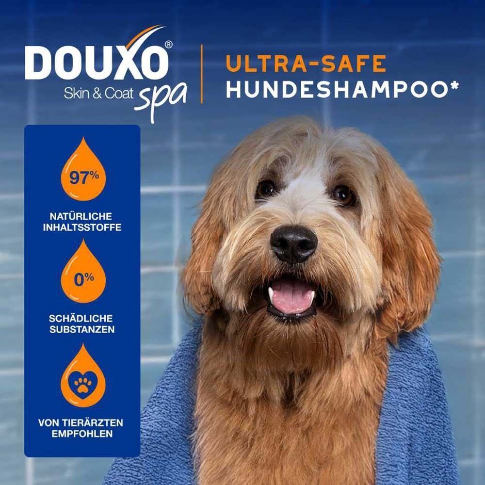 Hund mit Handtuch. Text: DOUXO Skin & Coat spa. Ultra-safe Hundeshampoo. 97% natürliche Inhaltsstoffe. 0% schädliche Substanzen.