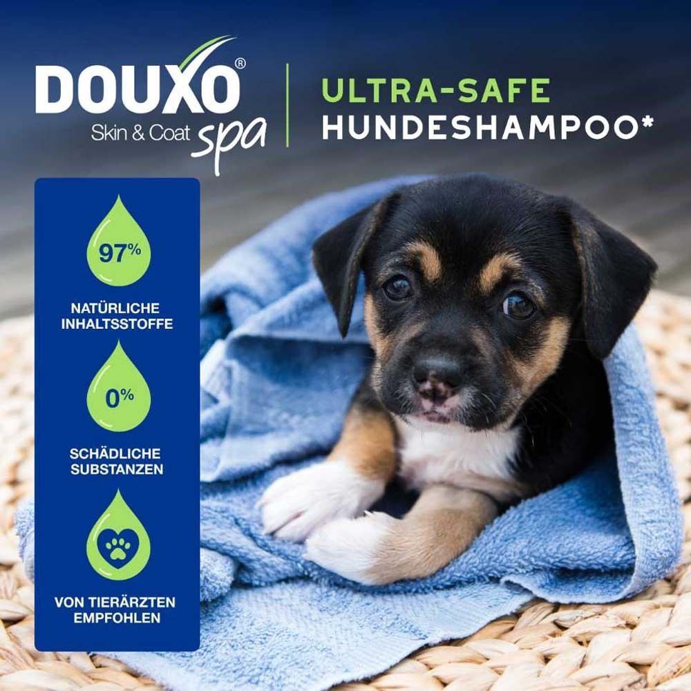 Ein Welpe in einem blauen Handtuch. Text: DOUXO Skin & Coat spa, Ultra-safe Hundeshampoo. Von Tierärzten empfohlen.