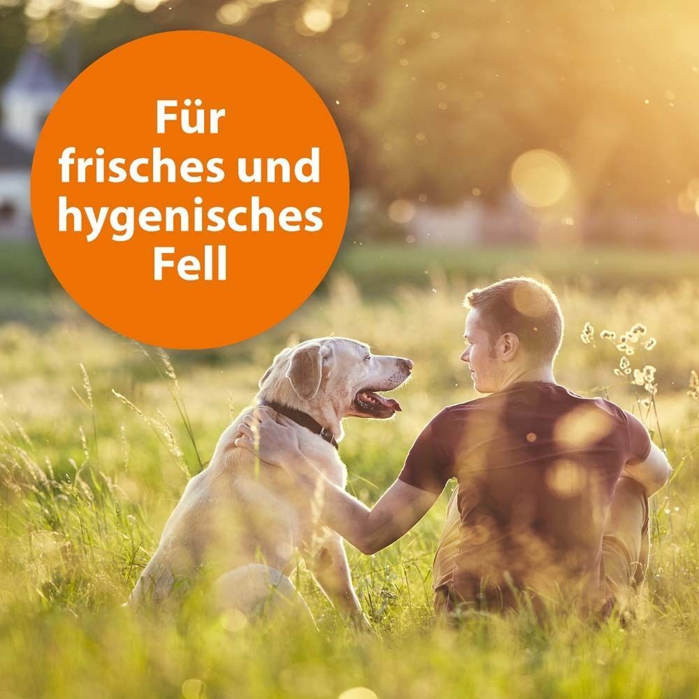 Ein Mann sitzt im Gras und streichelt einen Hund. Oranger Kreis mit Text: Für frisches und hygienisches Fell.
