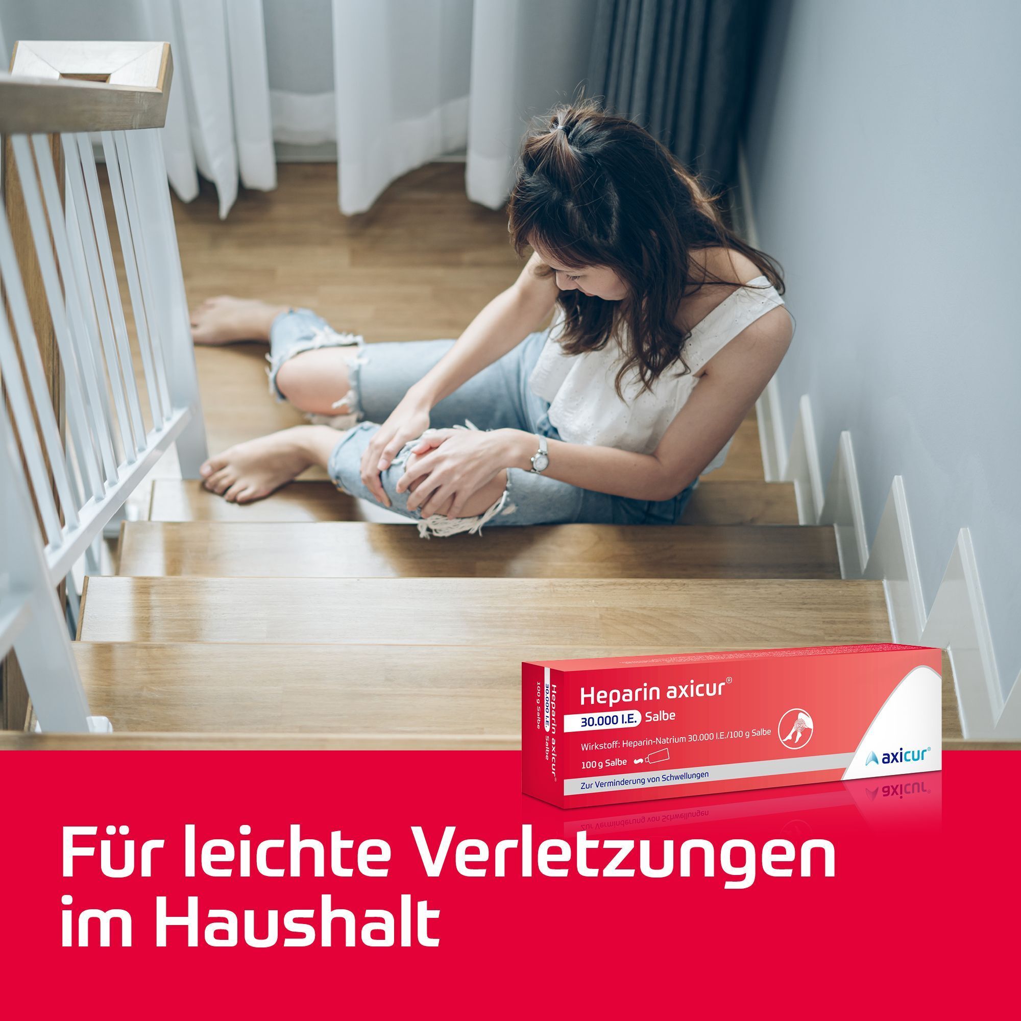 Frau sitzt auf Treppe nach Sturz, hält Knie, daneben Heparin axicur® Salbe.