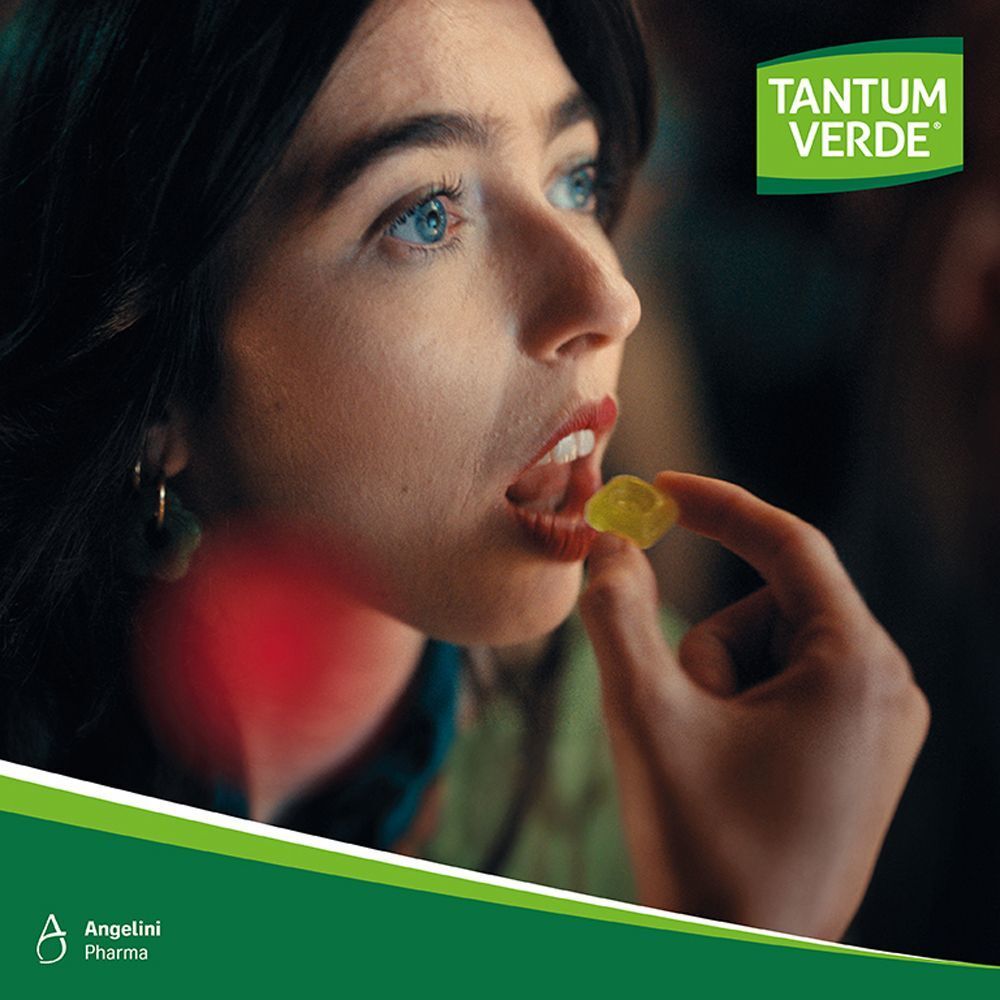 Frau nimmt eine Tantum Verde Lutschtablette ein, mit rotem Bereich am Hals.