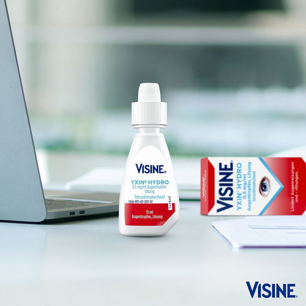 VISINE YXIN® HYDRO Augentropfen Flasche und Packung auf einem Schreibtisch neben einem Laptop.