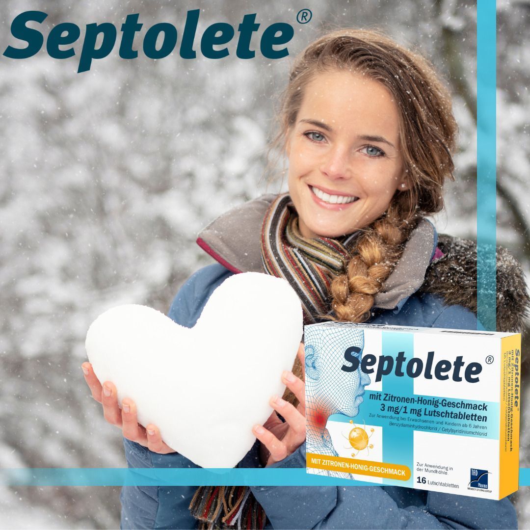 Lächelnde Frau im Schnee mit Herz aus Schnee und Septolete Lutschtabletten Zitrone-Honig.