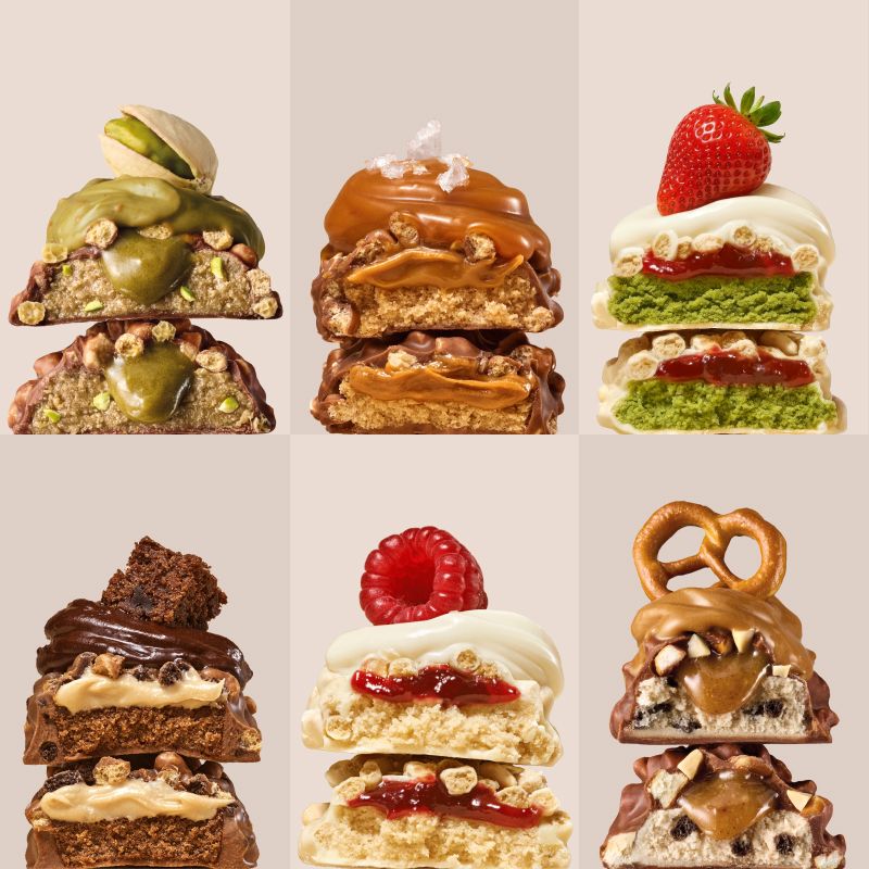 Sechs gestapelte Proteinriegel-Varianten, darunter Erdbeer-Matcha mit frischer Erdbeere.