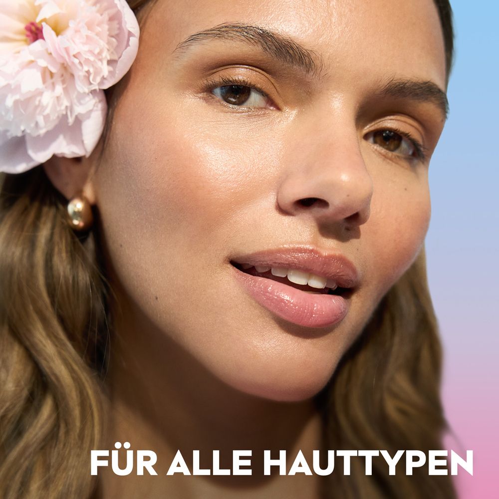 Nahaufnahme einer Frau mit einer Blüte im Haar und dem Schriftzug "FÜR ALLE HAUTTYPEN".