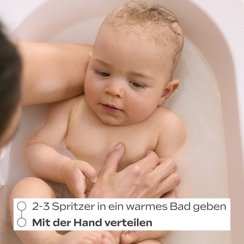Ein Baby in der Badewanne, dem mit der Hand ein Bad gegeben wird. Text: 2-3 Spritzer in ein warmes Bad geben.