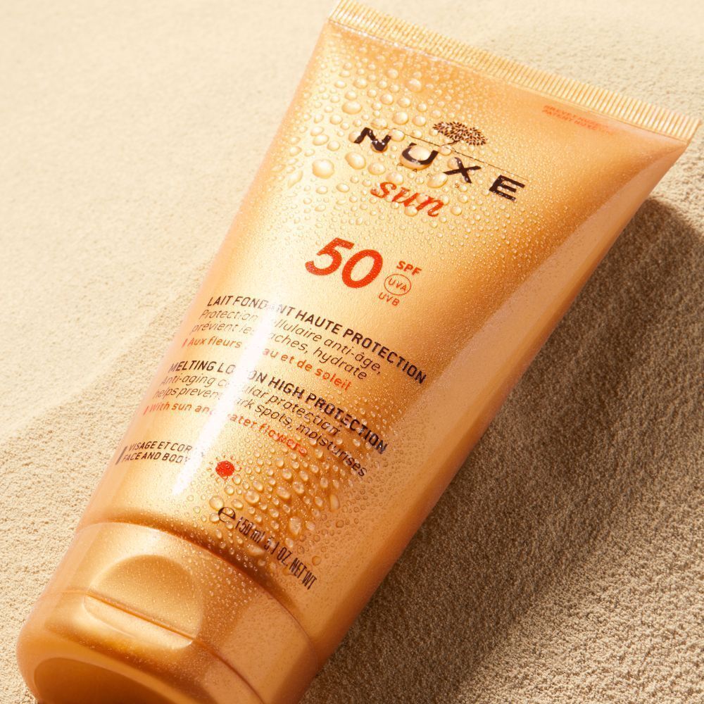 Tube NUXE Sun Sonnenmilch LSF 50 auf Sand, bedeckt mit Wassertropfen.