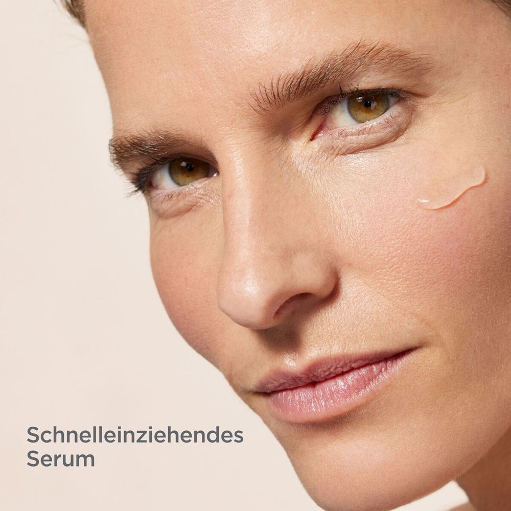 Nahaufnahme eines Gesichts mit einem Tropfen Serum. Text: Schnelleinziehendes Serum.