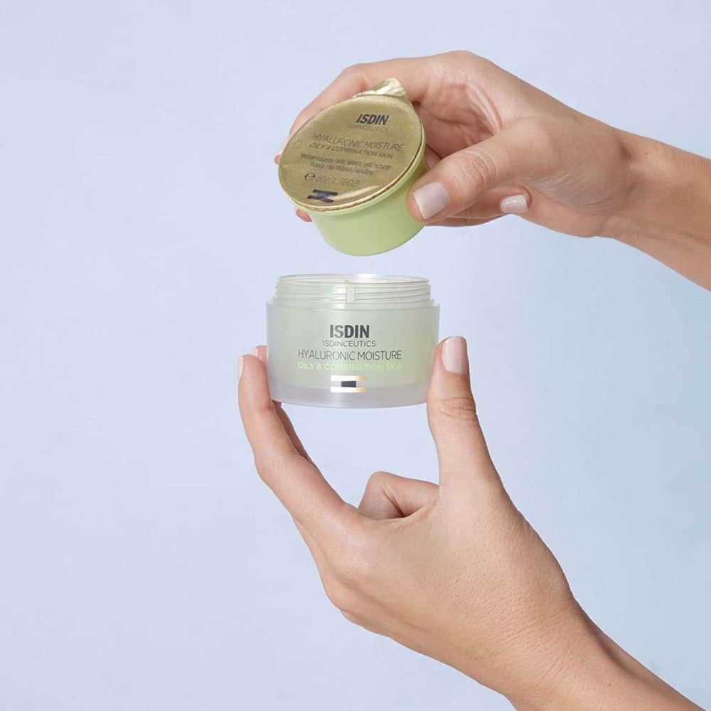 Hände öffnen einen ISDINCEUTICS Hyaluronic Moisture Tiegel für fettige Haut und Mischhaut, der eine Nachfüllpackung enthält.