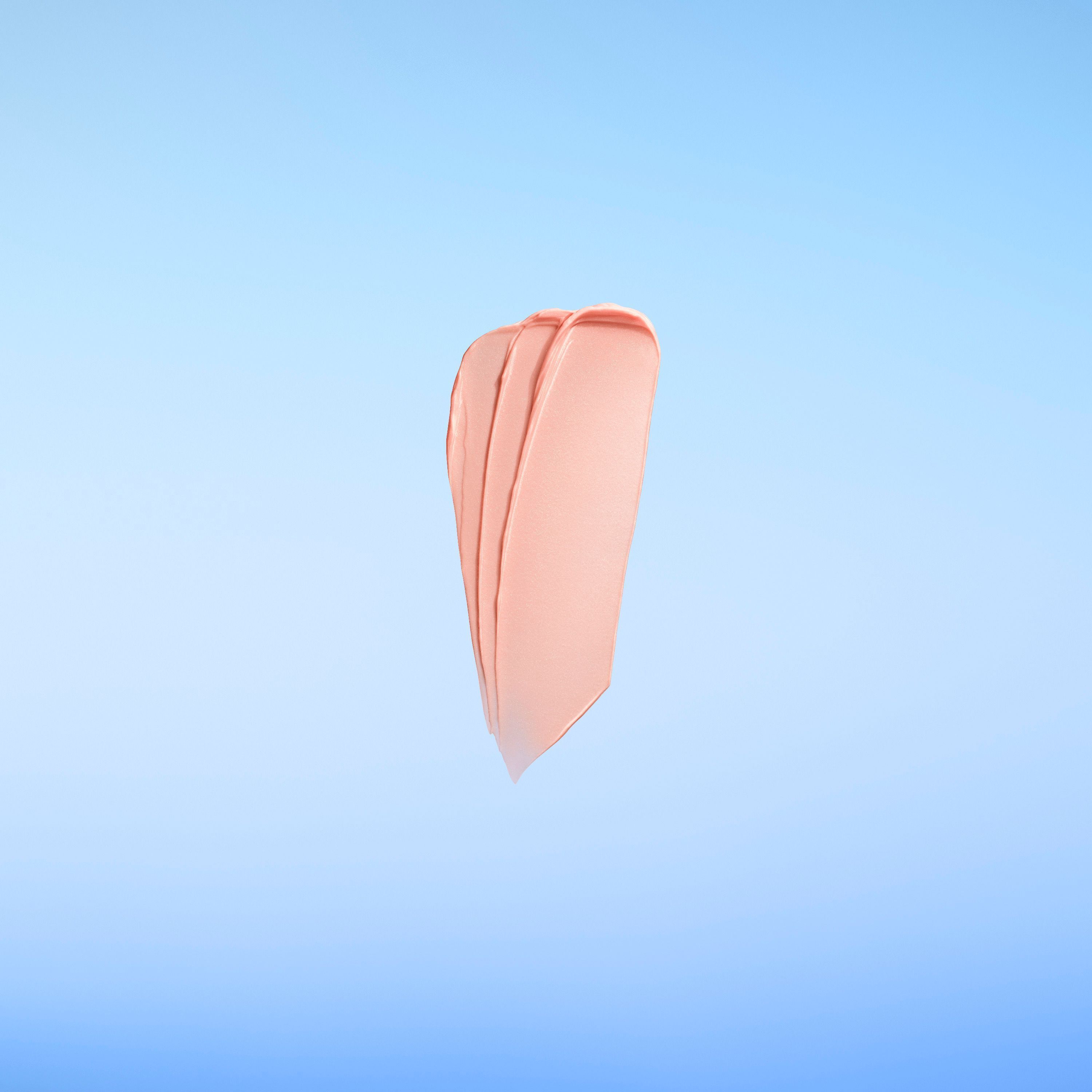 Eine cremige Texturprobe in Rosa auf blauem Hintergrund.
