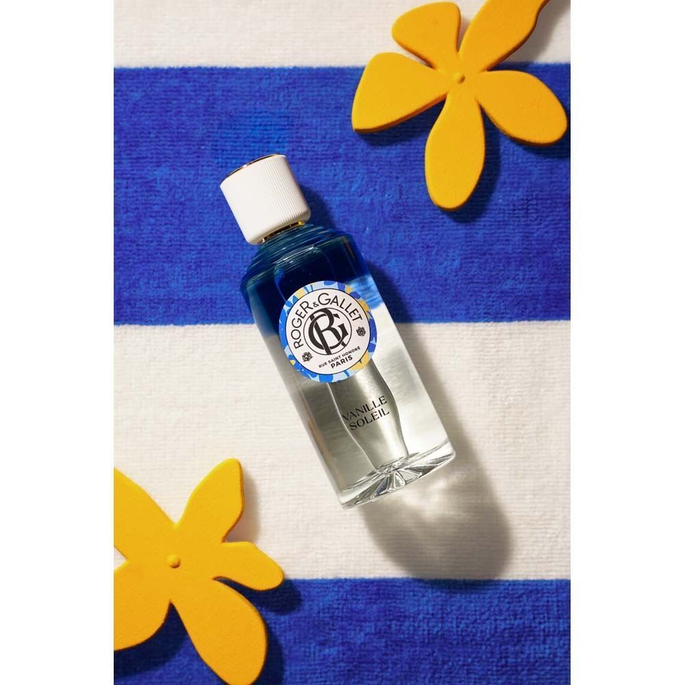ROGER&GALLET Vanille Soleil Wohlfühlwasser Flasche auf einem gestreiften Handtuch mit Blumen.