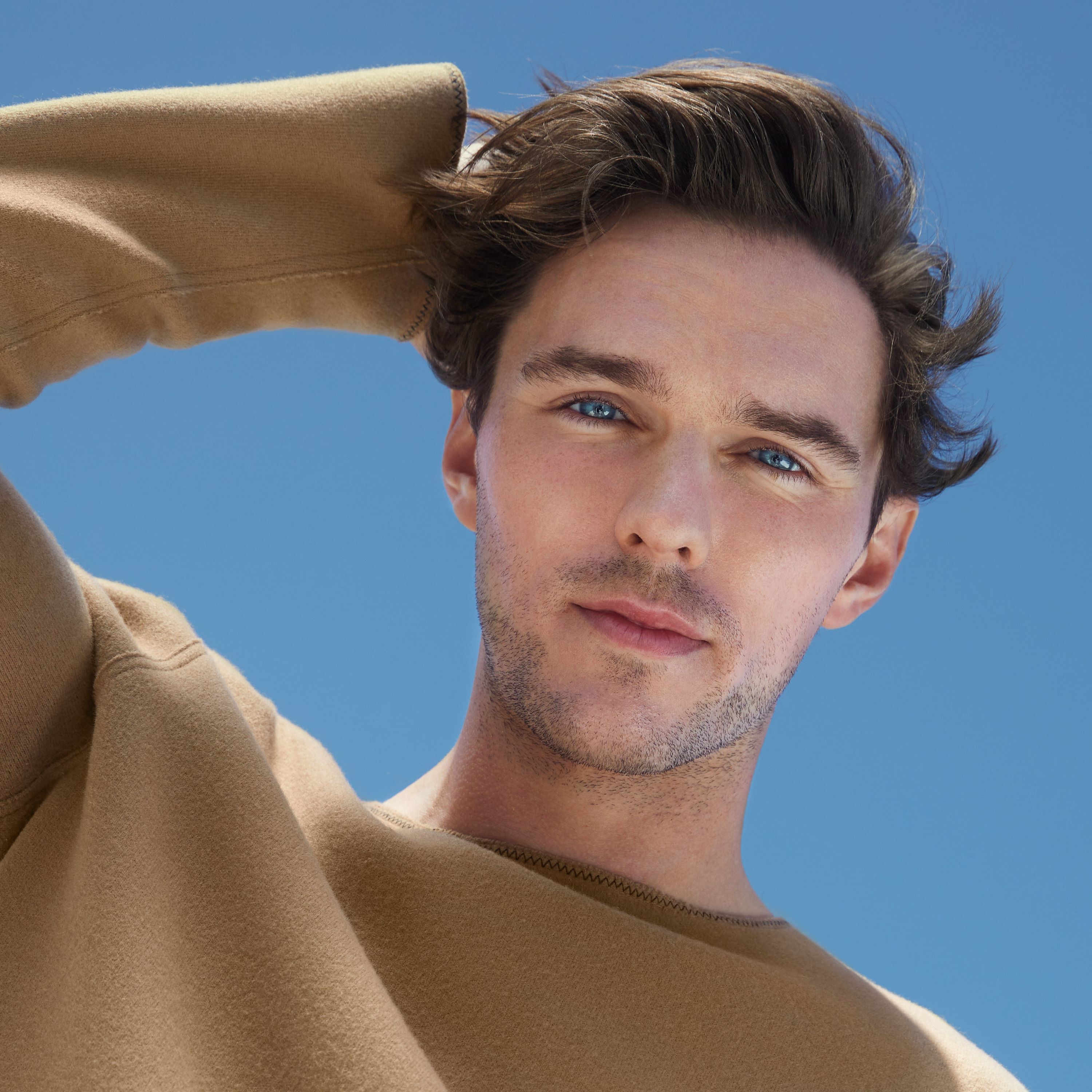 Porträt eines Mannes mit blauen Augen und braunem Pullover.