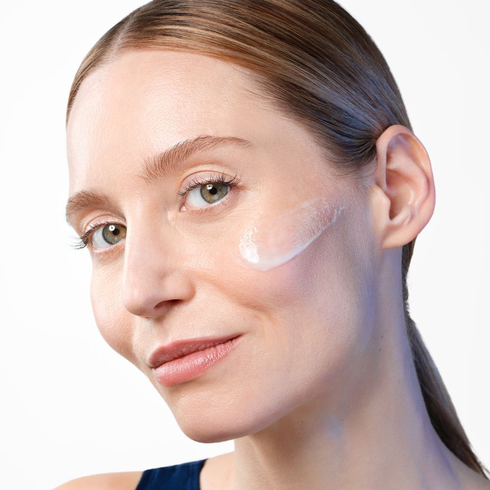 Frau mit Gallinee Youthful Cream auf der Wange, leichte Textur sichtbar.