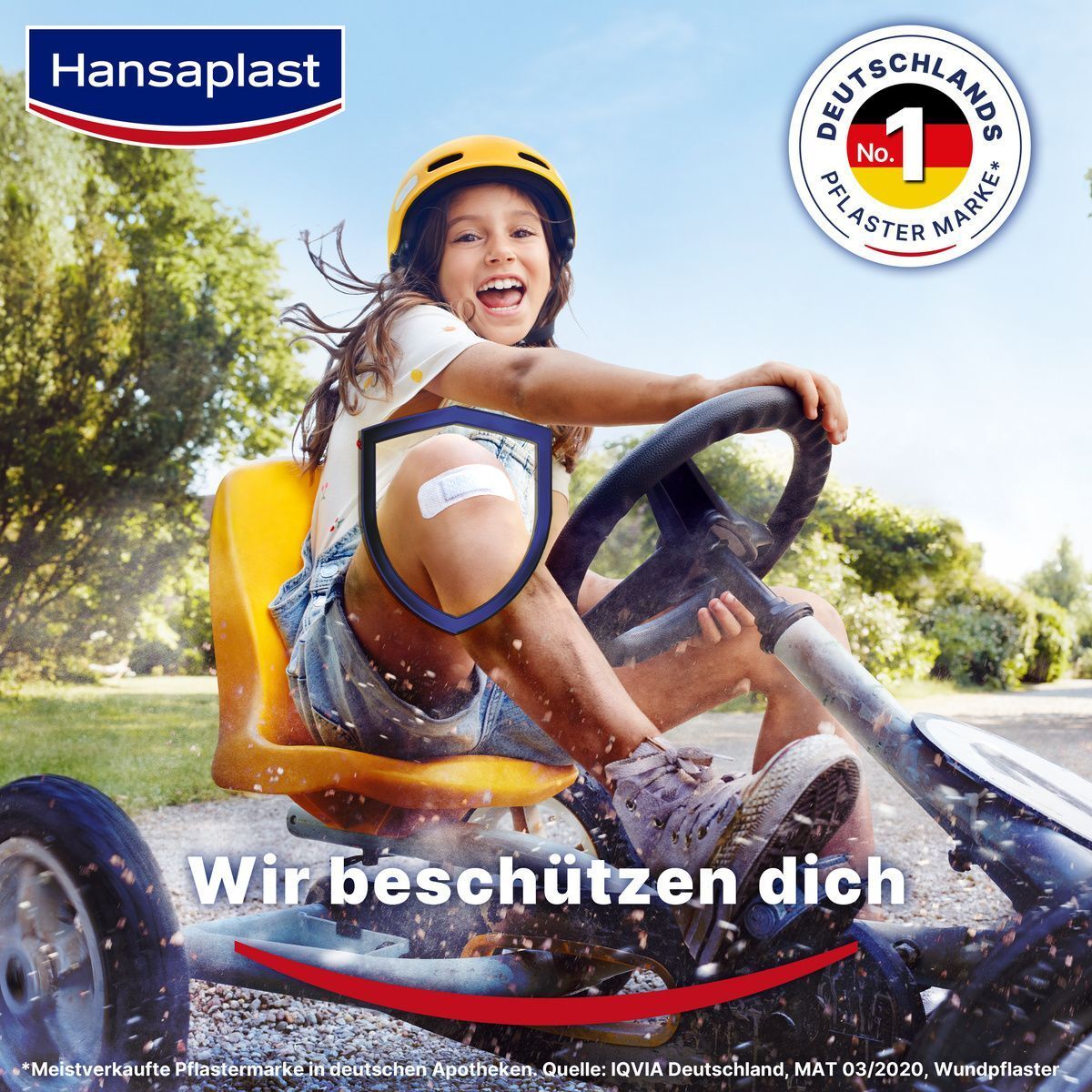 Kind fährt Go-Kart mit Hansaplast Pflaster auf dem Knie. "Wir beschützen dich".