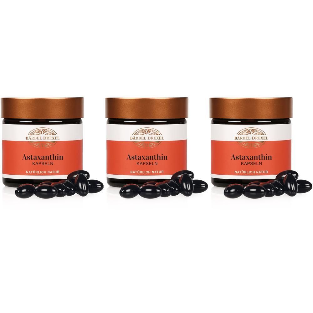 Drei Gläser Bärbel Drexel Astaxanthin Kapseln mit verstreuten Kapseln davor.