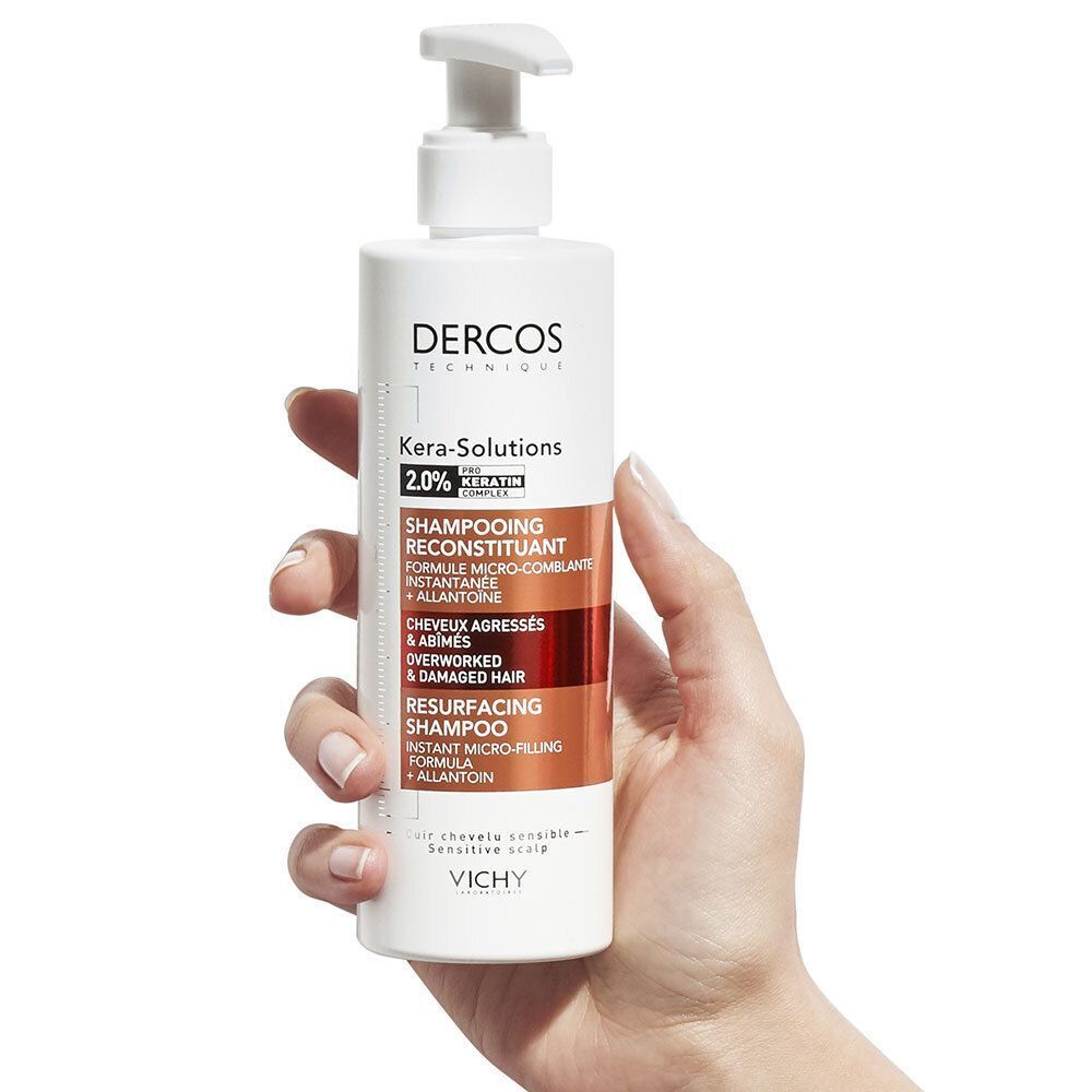 Hand hält eine weiße Pumpspenderflasche Vichy Dercos Kera-Solutions Shampoo mit Keratin-Komplex.