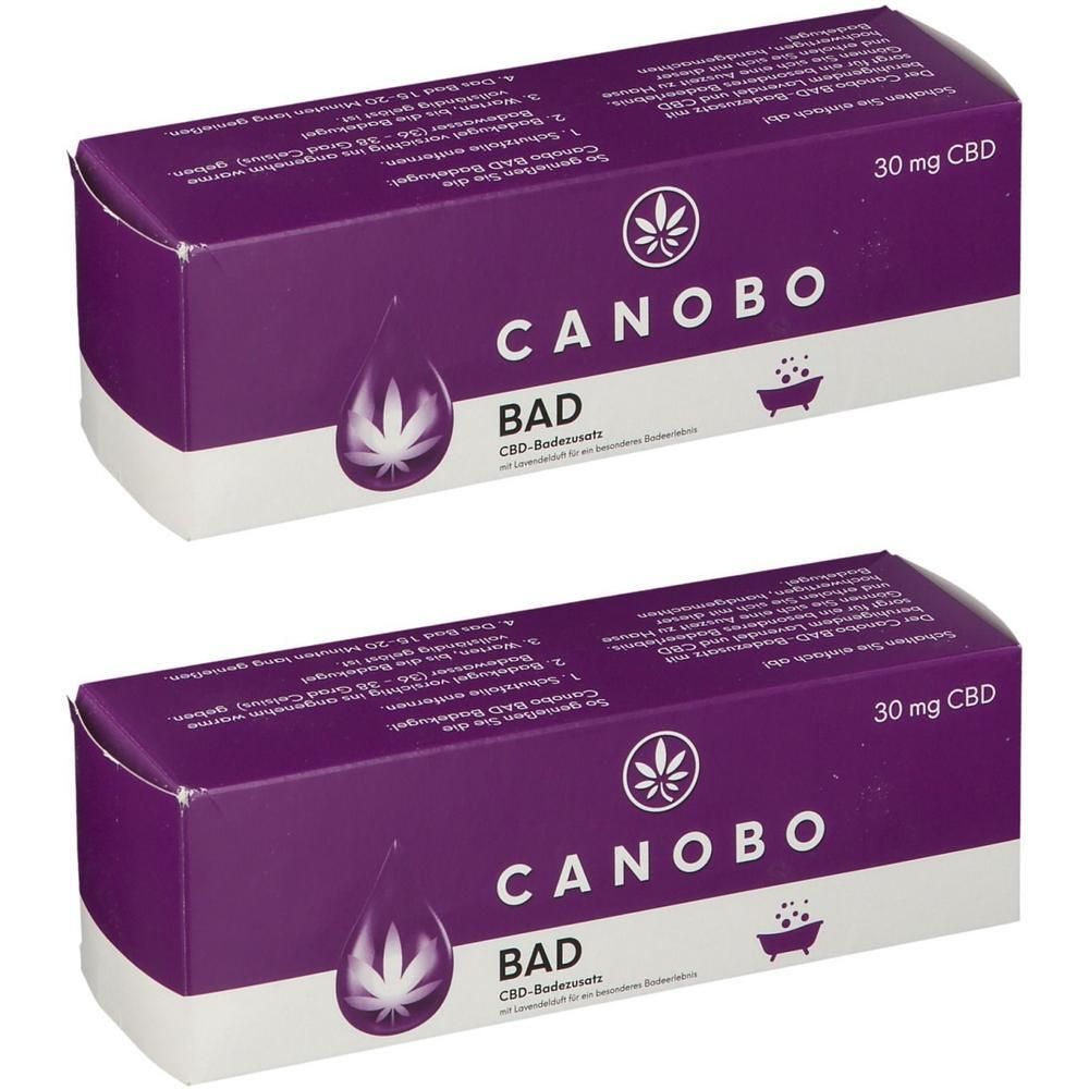 Zwei Packungen CANOBO BAD CBD-Badezusatz mit je 30 mg CBD. Lila Kartonverpackung mit weißem Aufdruck.