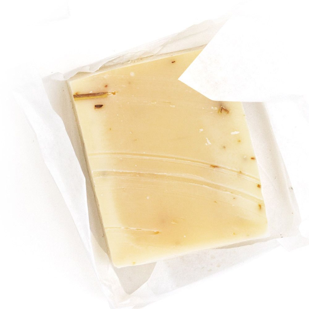 Eine Packung Lemongras-Seife, Seife in Folie verpackt. Gelbliche Seife mit sichtbaren Pflanzenpartikeln.
