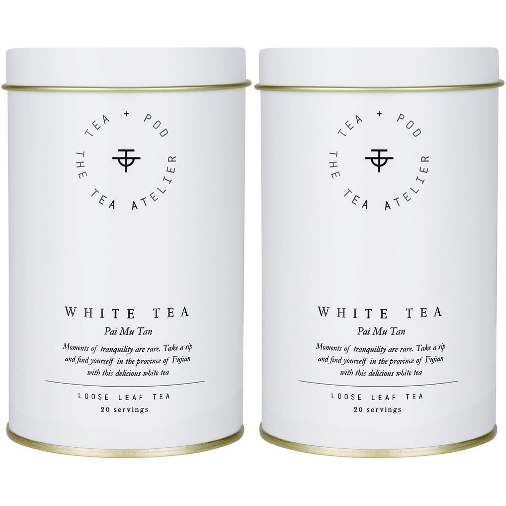 Zwei weiße Teedosen mit goldenen Rändern. Beide zeigen das Logo 'The Tea Atelier' und die Aufschrift 'White Tea'.