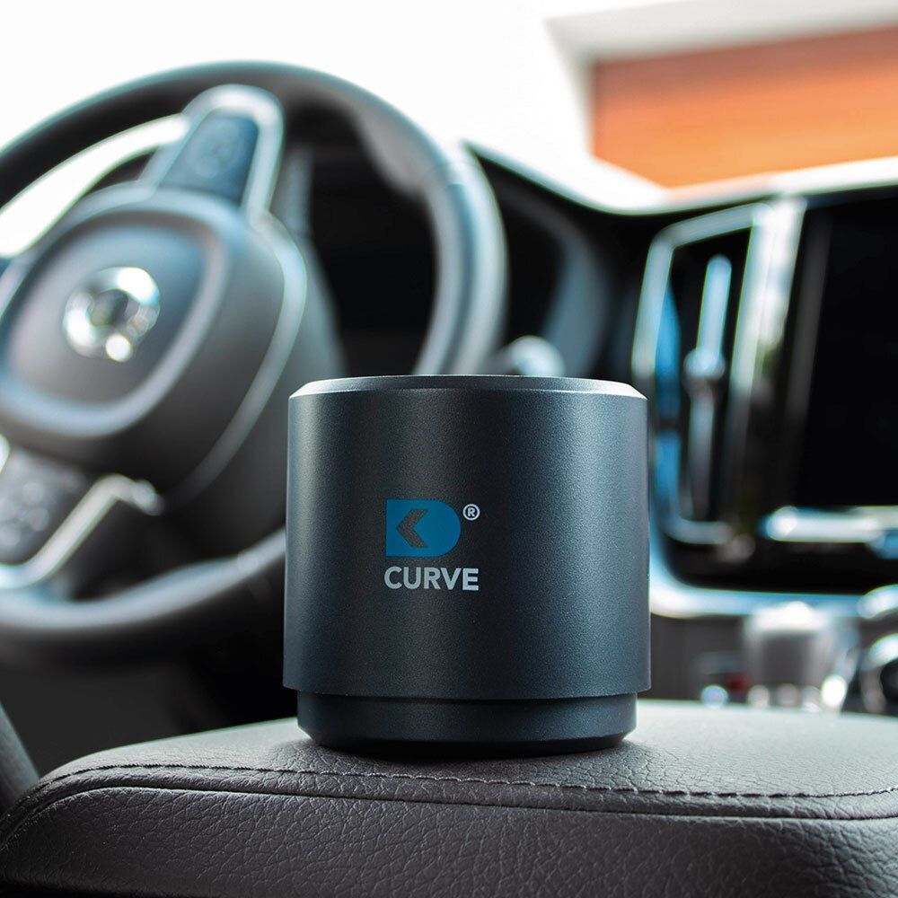 CURVE Luftreiniger auf dem Armaturenbrett eines Autos, neben dem Lenkrad.
